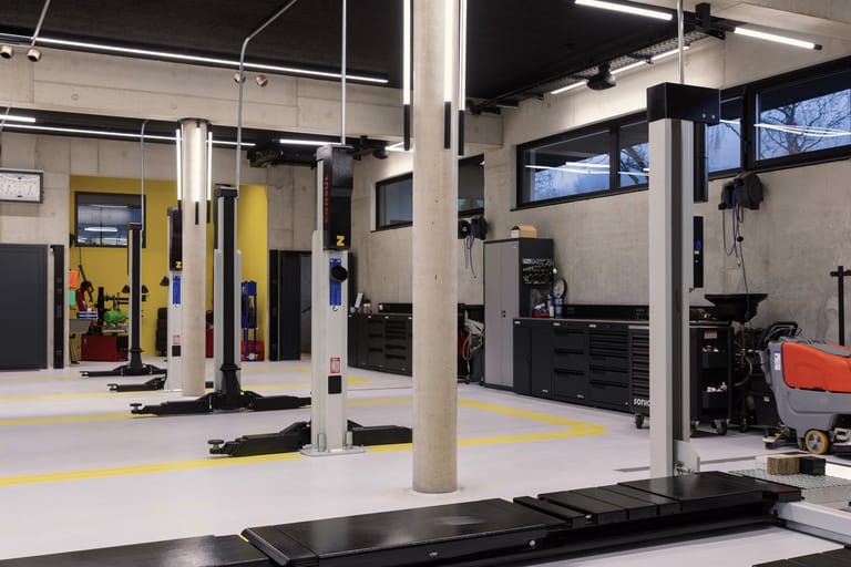 Große, moderne Kfz-Werkstatt mit Hebebühnen und gelben Markierungen