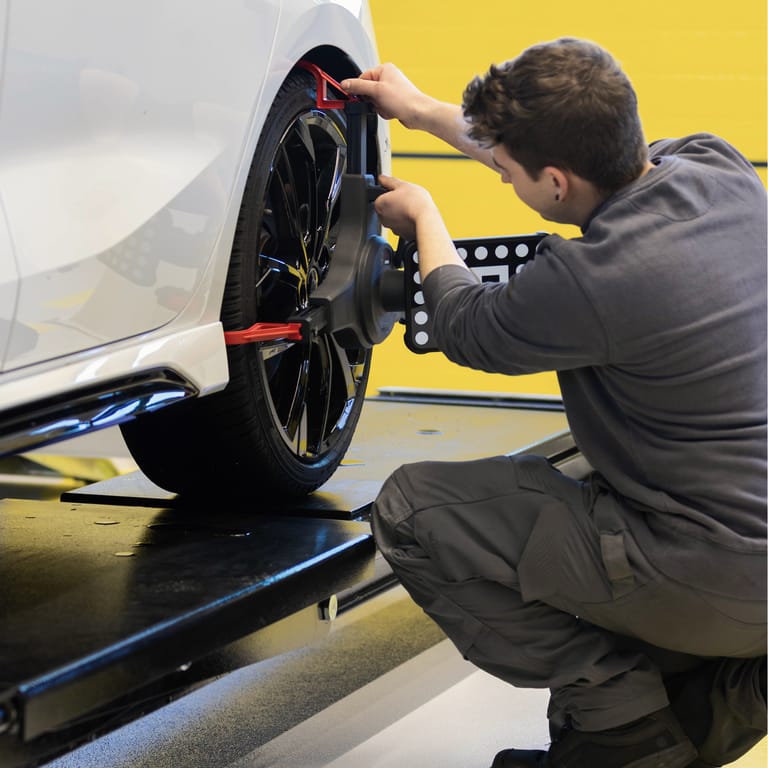 Mechaniker führt Achsvermessung an einem Fahrzeug durch